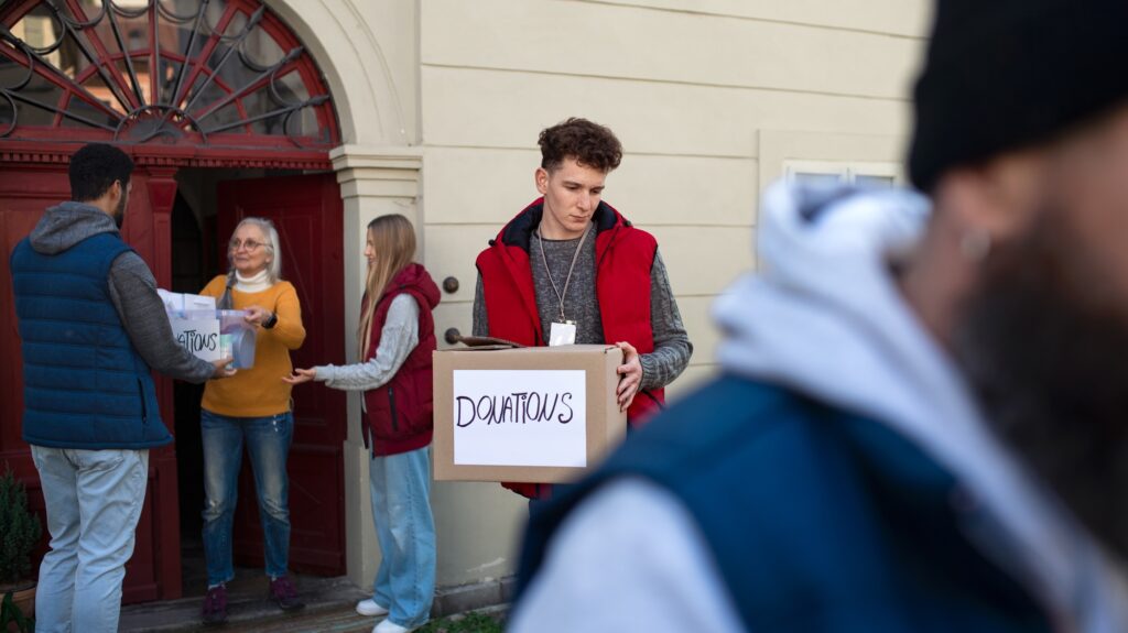 Diverse group of volunteers with donation boxes standing outdoors, social care and charity concept