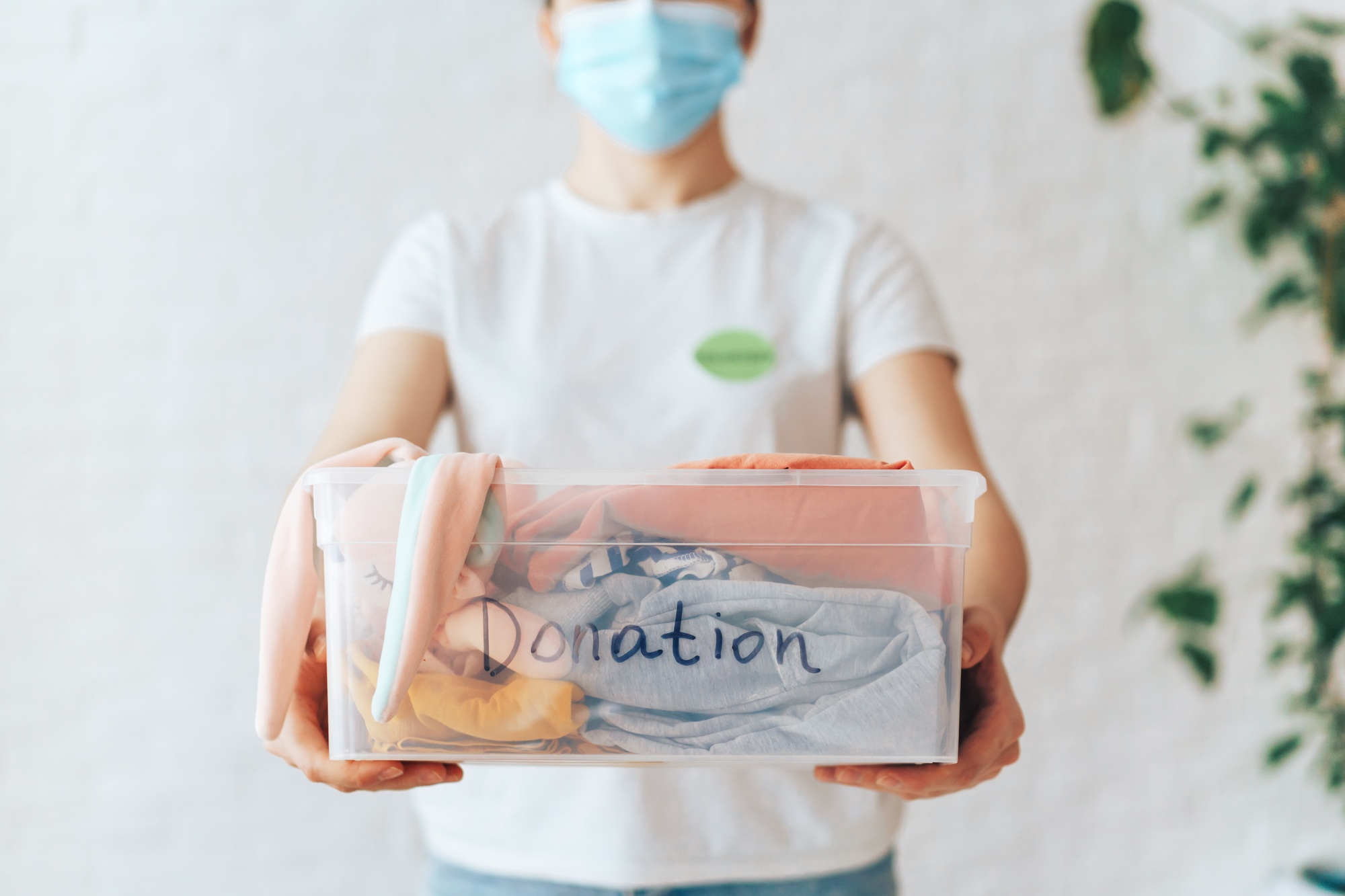 Girl holds out plastic container with the inscription donation